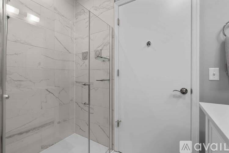 A bathroom with a marble wall and a white door.