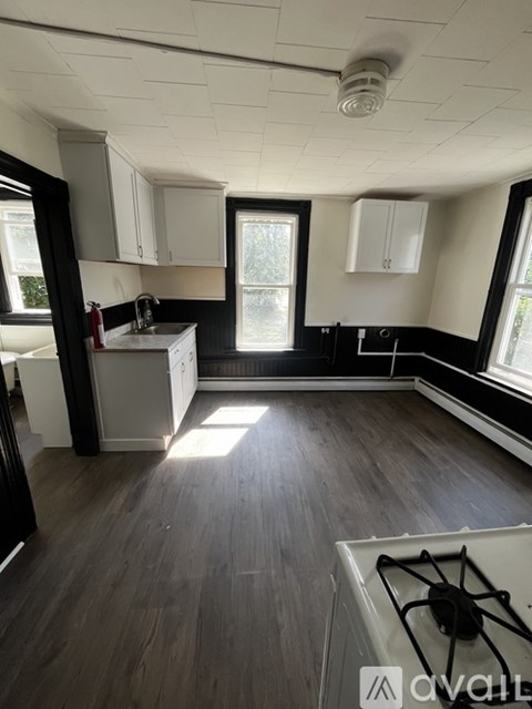 A kitchen with a white stove top oven and wooden flooring.