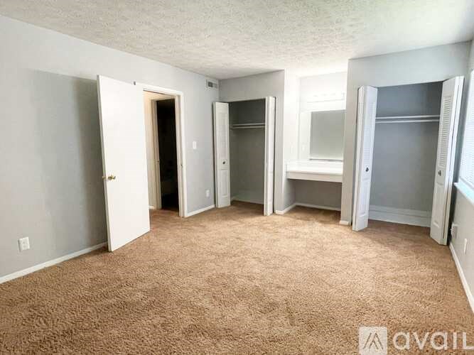 A room with carpeted floor and white walls, with a doorway leading to another room.