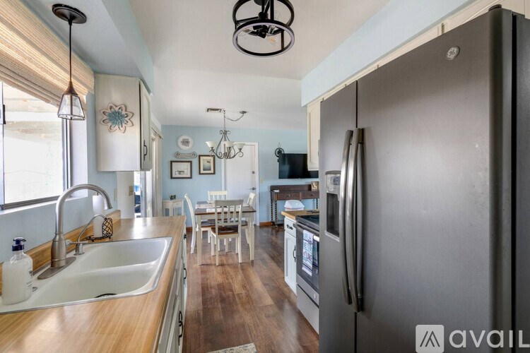 A kitchen with a sink, refrigerator, and dining area.