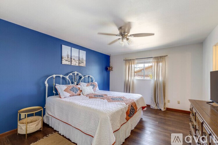 A bedroom with blue walls and a white bed.