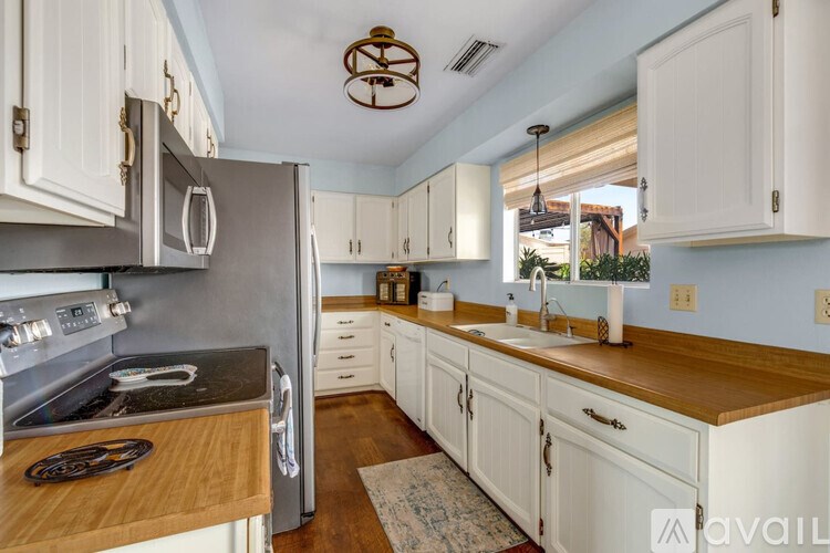 A kitchen with white cabinets and a wooden countertop.