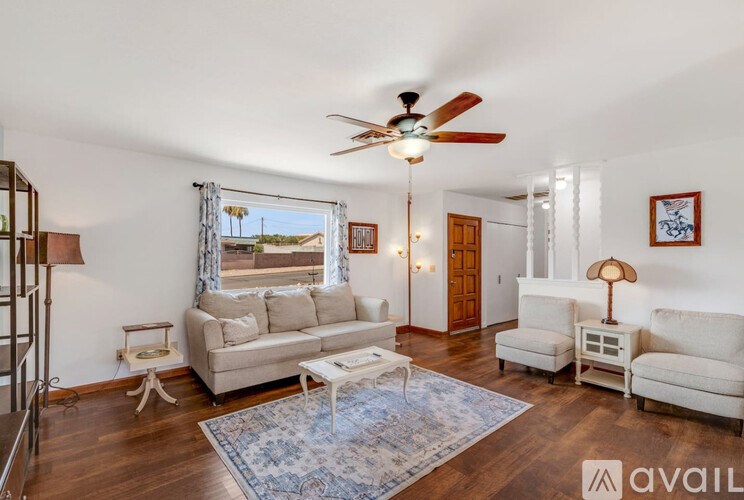 A living room with a fan, a couch, and a chair.