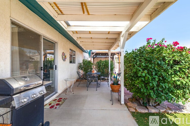 A patio with a grill and chairs under a roof.