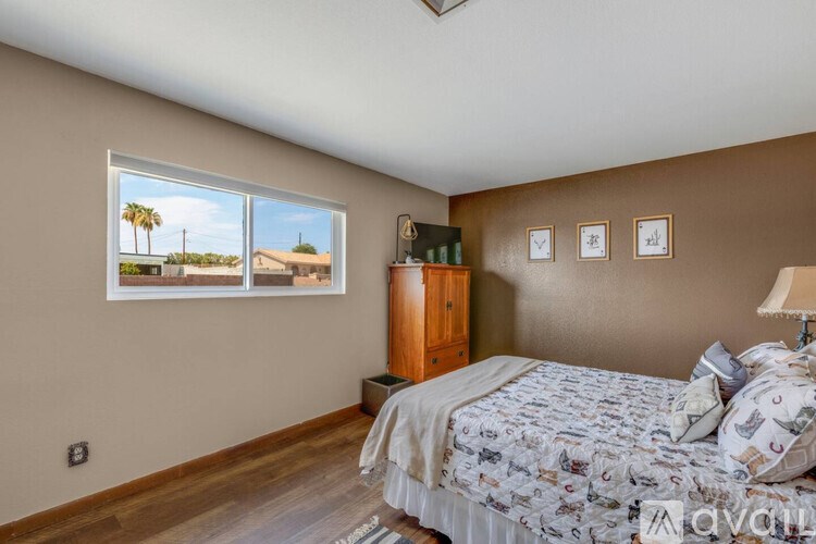 A bedroom with a large bed and a window overlooking a palm tree.