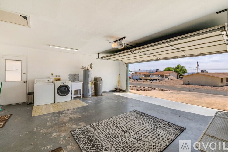 A large open garage with a washing machine and dryer stacked on top of each other.