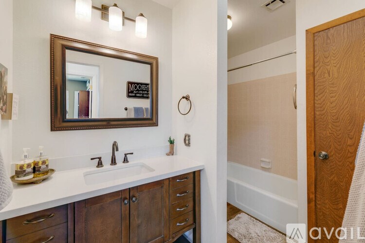 A bathroom with a sink, mirror, and wooden cabinets.