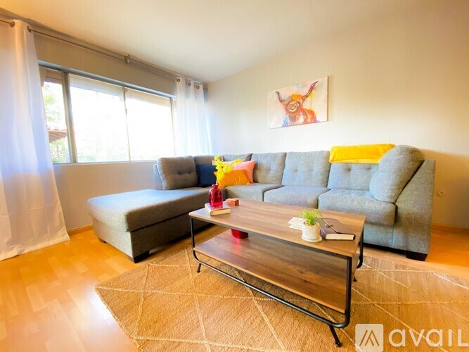 A living room with a grey couch, a coffee table, and a painting on the wall.