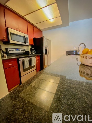 A kitchen with red cabinets and a black counter top.