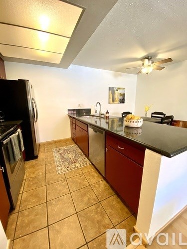 A kitchen with a black fridge and brown cabinets.