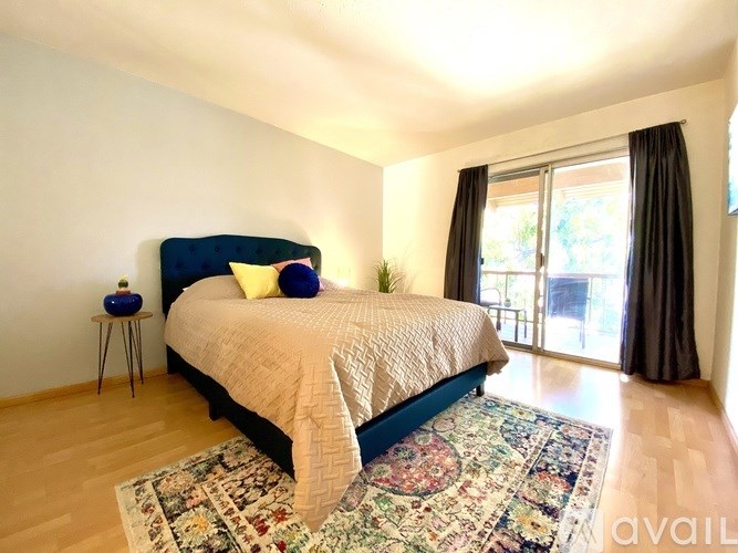 A bedroom with a large bed and a rug on the floor.