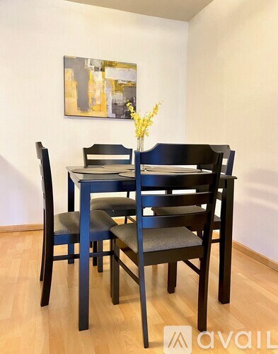 A dining table with four chairs and a vase of flowers on it.