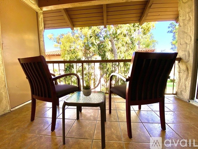 Two chairs and a table on a balcony.