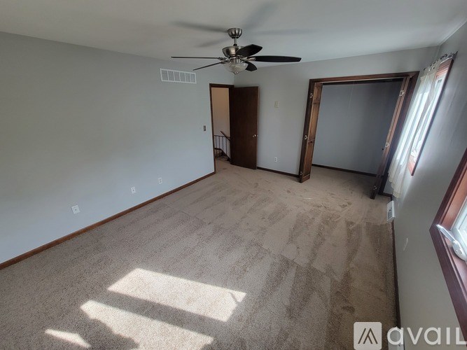 A room with a ceiling fan and carpeted floor.
