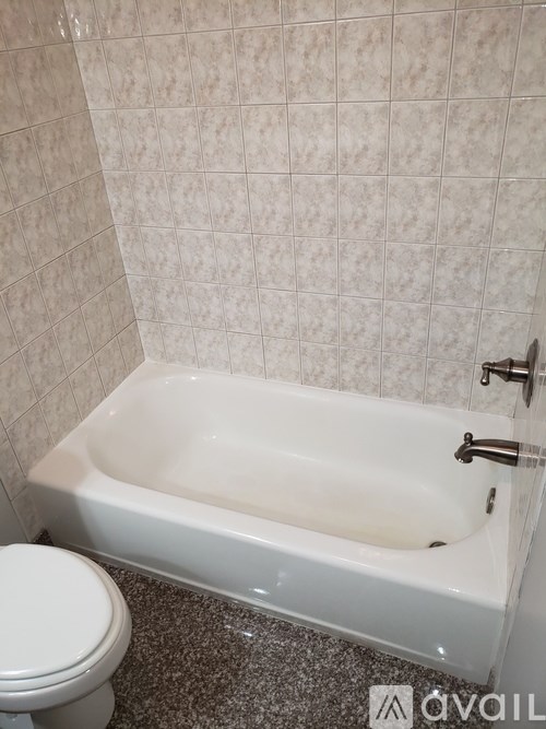 A white bathtub in a bathroom with a toilet next to it.