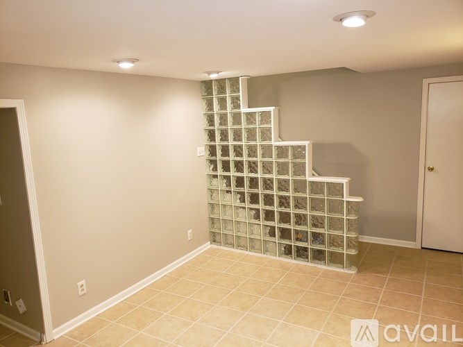 A glass block staircase in a room with beige walls and tiled flooring.