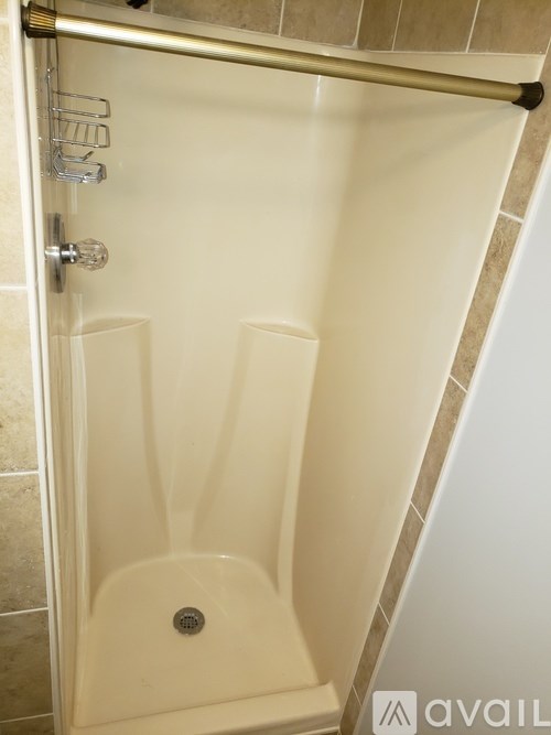 A white shower stall with a door and a handle.