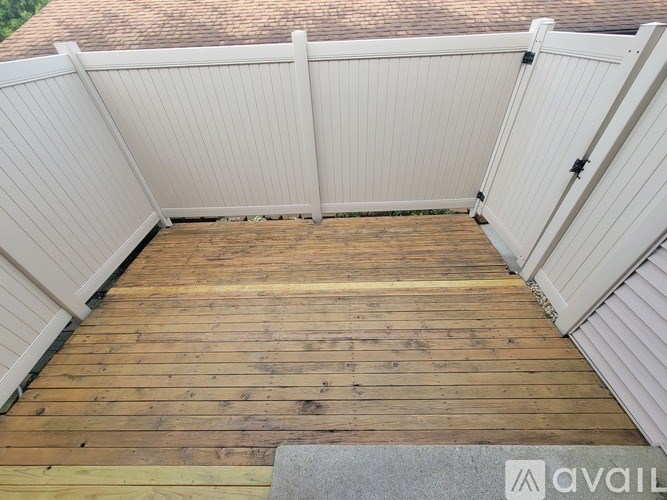 A wooden deck with a white fence and a grey rug.