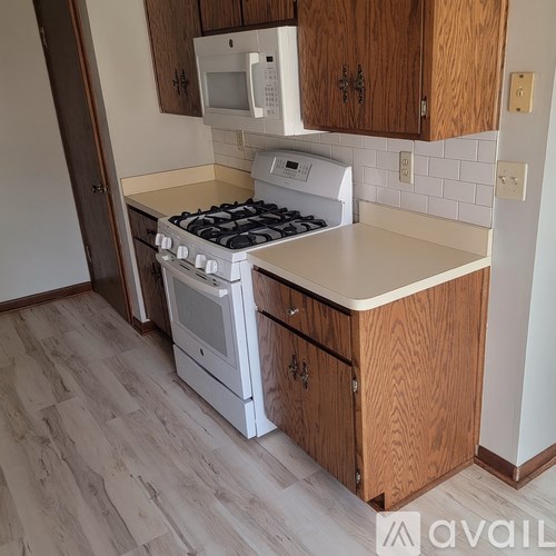 A kitchen with a white stove and wooden cabinets.