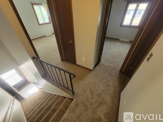 A carpeted hallway with a staircase leading to the second floor.