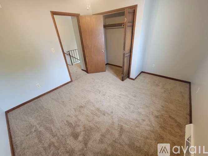 A carpeted room with a door and a mirror.