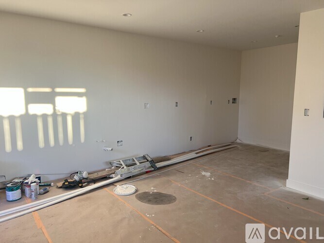 A room with a lot of white walls and a floor that is half painted.