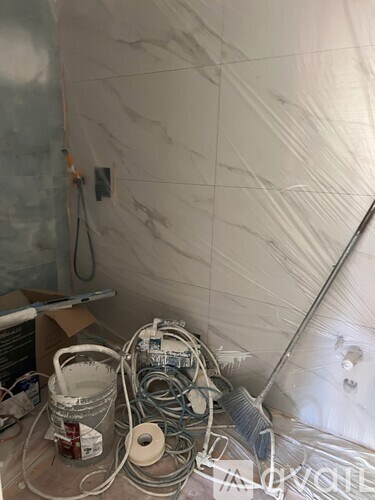 A room with a white bucket, rolls of tape and other items on the floor.