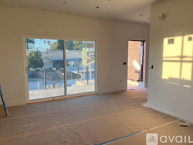 A room with a large window and a door is available for rent.