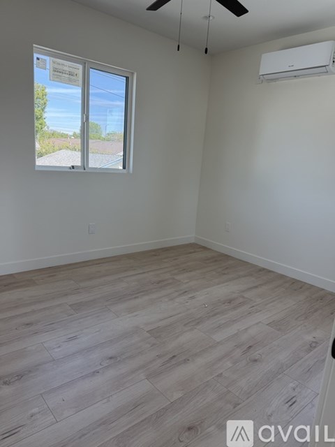 A room with a large window and a door is available for rent.