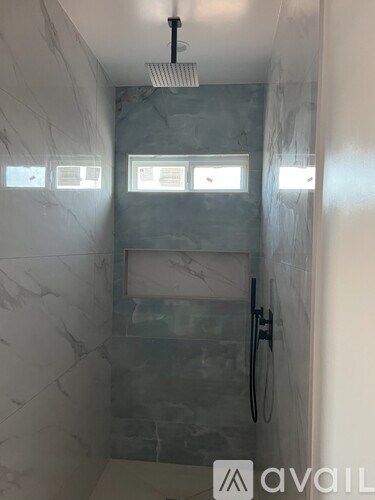 A bathroom with marble tiles and a glass shower stall.