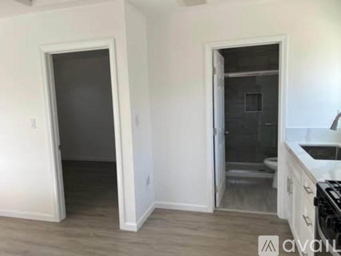 A kitchen area with a sink and a door leading to a bathroom.