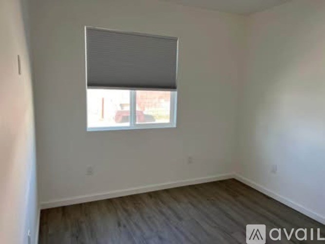 A room with a window and wooden flooring is available for rent.