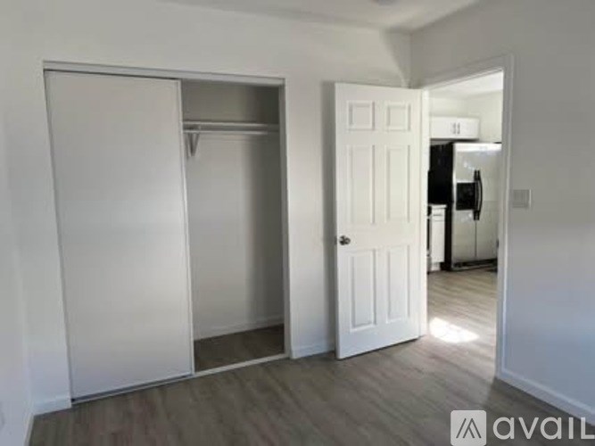 A white door is open to a room with a white wall and a white closet.
