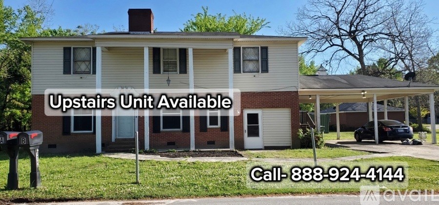 A house with a sign that says "Upstairs Unit Available" and a phone number.
