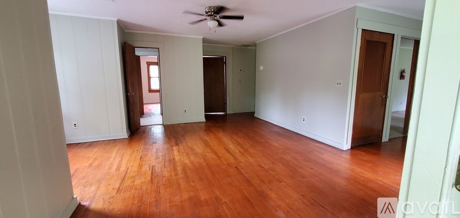 A room with wooden floors and white walls is available for rent.