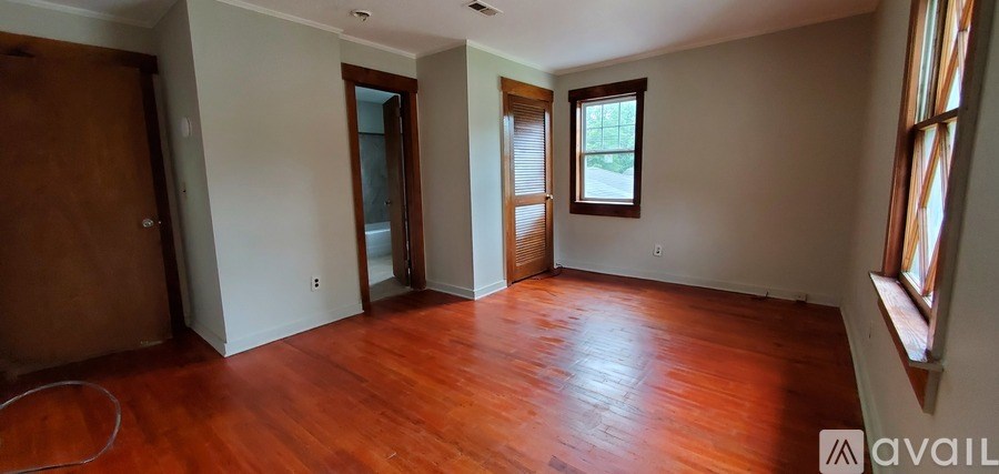 A room with wooden floors and a window with blinds.