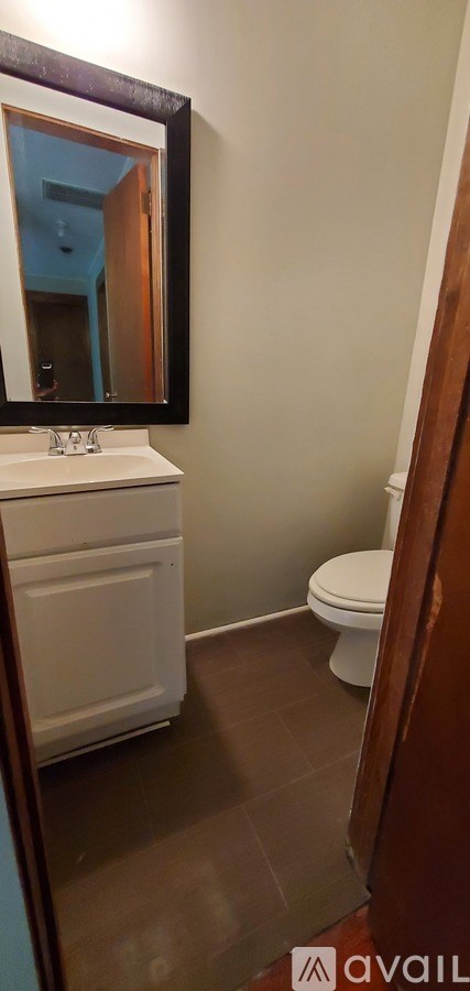 A bathroom with a toilet, sink, and mirror.