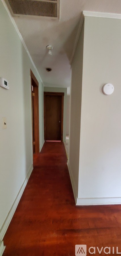 A long hallway with a brown floor and white walls.