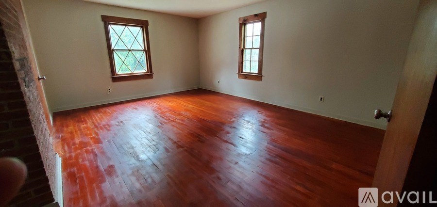 A room with wooden floors and two windows.