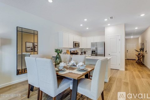 A dining room with a table set for two and a kitchen in the background.