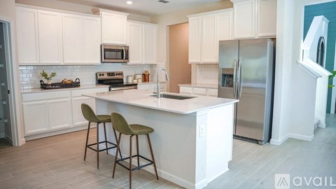 A kitchen with white cabinets and a white island with two chairs.