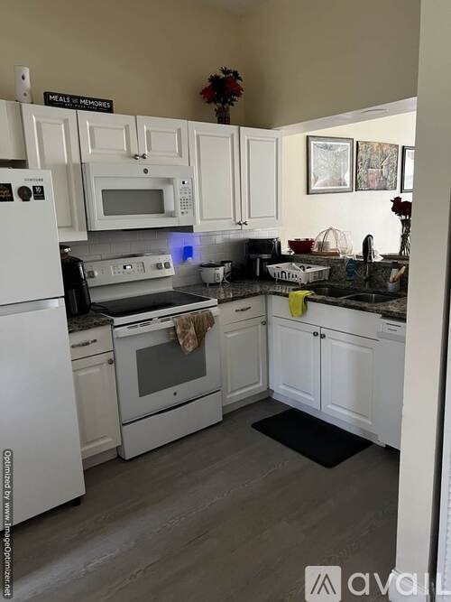 A kitchen with white appliances and cabinets.