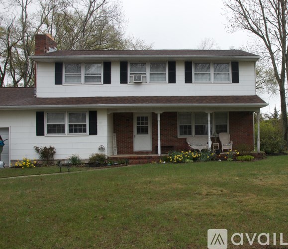 A white house with a brown roof and a red brick chimney.
