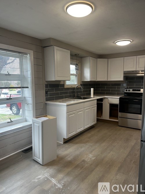 A kitchen with white cabinets and a wooden floor.