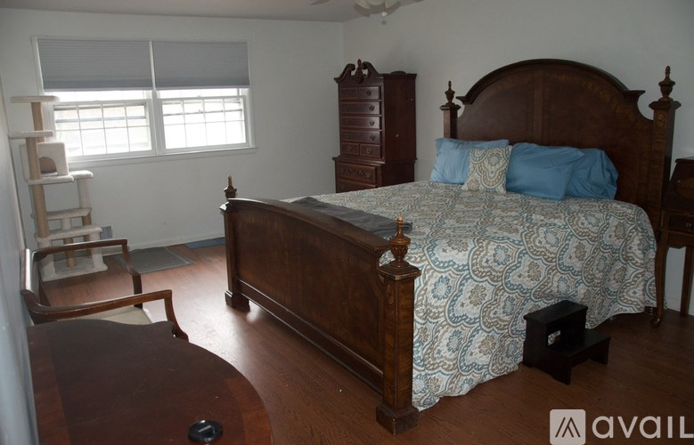 A bedroom with a bed, dresser, and window.