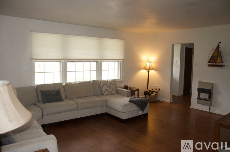 A living room with a couch, a table with a lamp, and a vase with flowers.