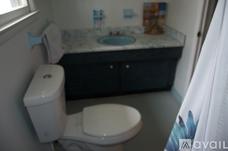 A bathroom with a toilet, sink, and cabinet.