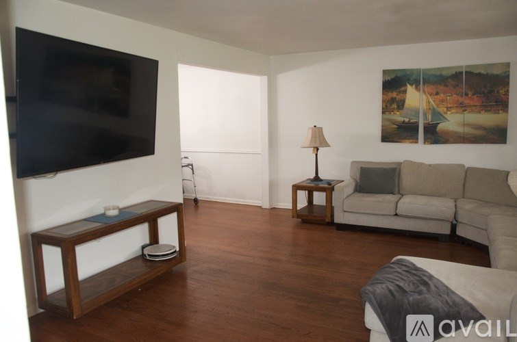 A living room with a couch, a television, and a painting on the wall.