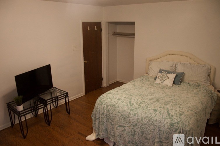 A bedroom with a bed, a chair, and a television.