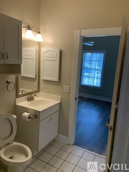 A bathroom with a toilet, sink, mirror and cabinet.
